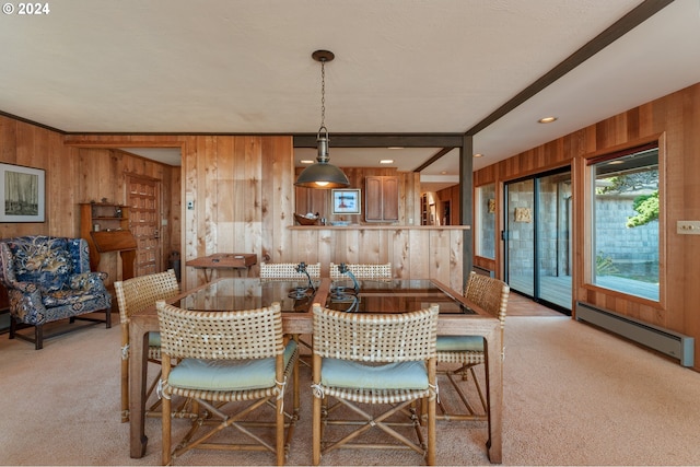 dining space featuring wood walls, a baseboard heating unit, and light colored carpet