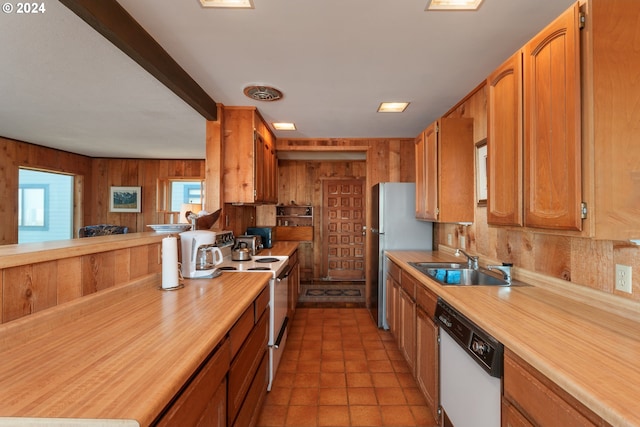 kitchen with white appliances, light tile patterned flooring, sink, and wooden walls