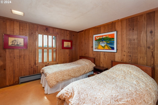 carpeted bedroom featuring wooden walls, a baseboard heating unit, and a textured ceiling