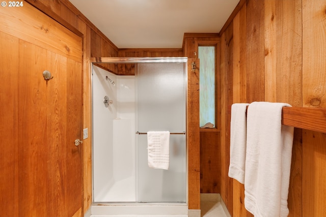 bathroom with a shower with shower door and wooden walls