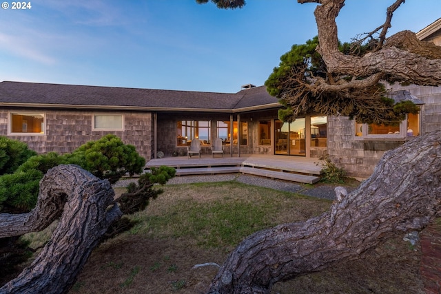 back of house with a deck and a lawn