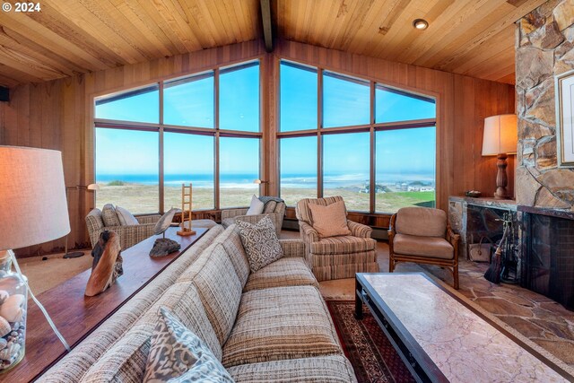 living room featuring wooden walls, a water view, and plenty of natural light