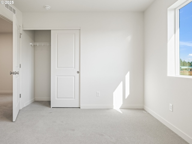 unfurnished bedroom with baseboards, visible vents, a closet, and light colored carpet