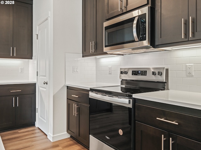 kitchen featuring light countertops, decorative backsplash, appliances with stainless steel finishes, light wood-style floors, and dark brown cabinetry