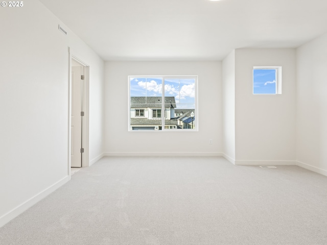 carpeted spare room with visible vents and baseboards