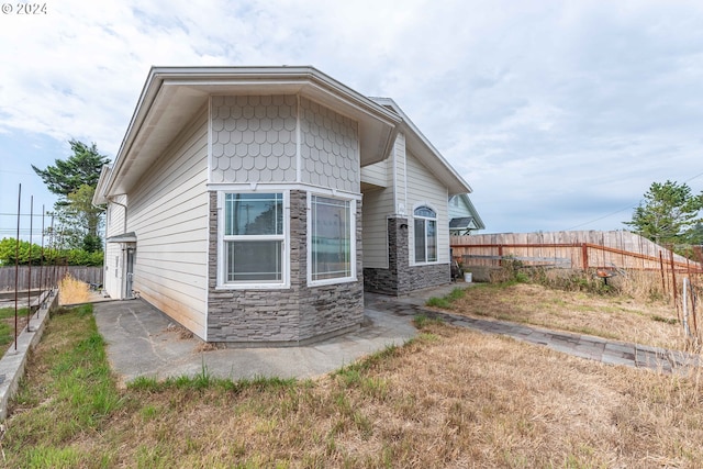 exterior space with stone siding and a fenced backyard