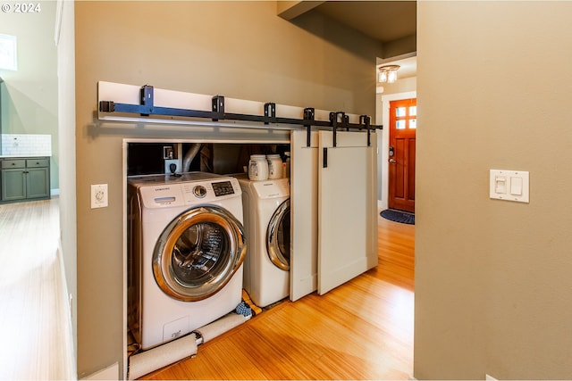 laundry room featuring light hardwood / wood-style floors, washer and clothes dryer, and a barn door