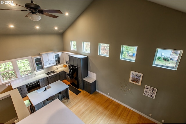 living room with ceiling fan, high vaulted ceiling, and light hardwood / wood-style flooring