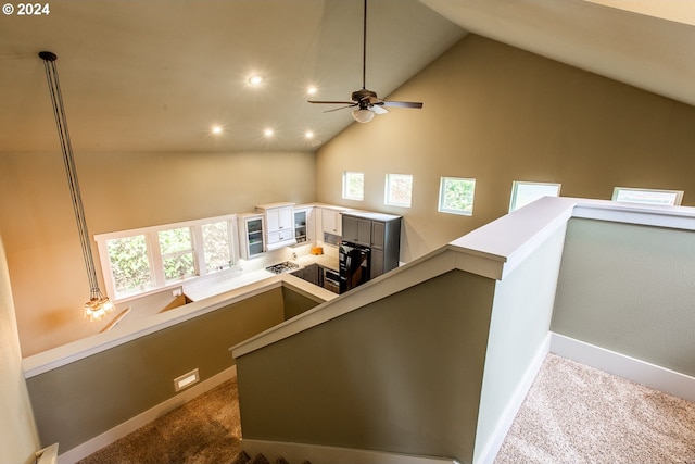 stairs with ceiling fan, a healthy amount of sunlight, carpet flooring, and high vaulted ceiling