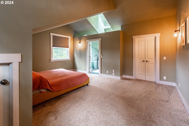 carpeted bedroom featuring lofted ceiling with skylight and connected bathroom