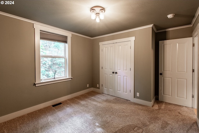 unfurnished bedroom with a closet, crown molding, a textured ceiling, and carpet floors