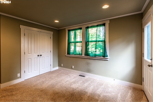 unfurnished bedroom with multiple windows, ornamental molding, and carpet