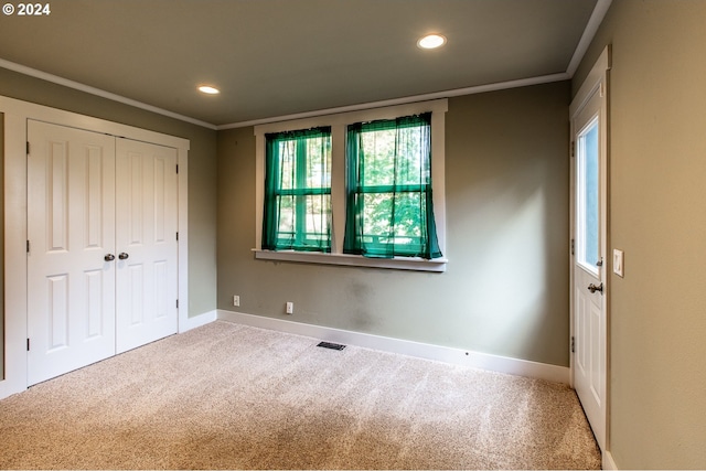 unfurnished bedroom featuring crown molding, a closet, and carpet