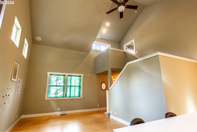 interior space with ceiling fan, high vaulted ceiling, and light wood-type flooring