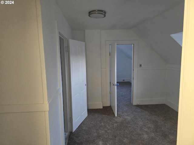 hall featuring lofted ceiling and dark colored carpet