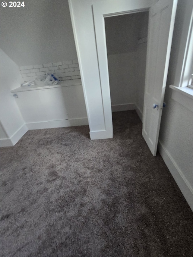 unfurnished bedroom with a closet and dark carpet