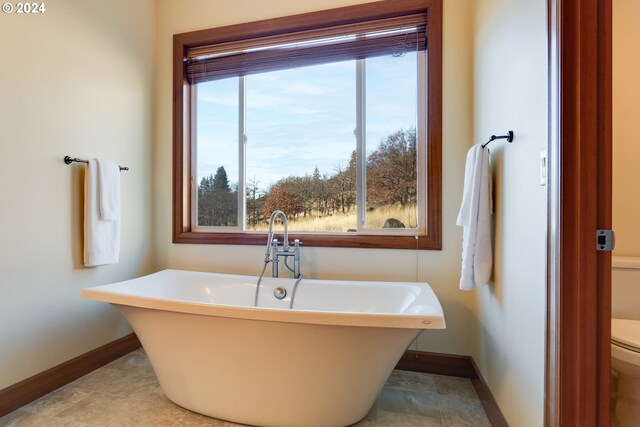 bathroom with tile patterned floors, toilet, and a tub to relax in