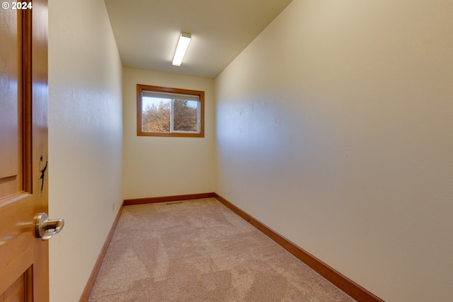 unfurnished room with baseboards and light colored carpet