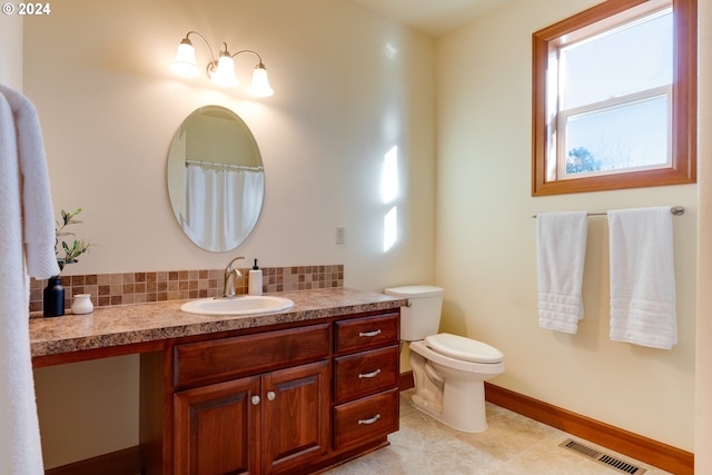 bathroom with tile patterned flooring, vanity, tasteful backsplash, and toilet