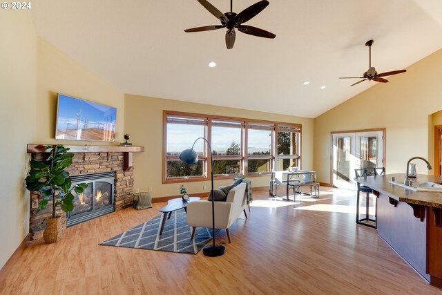 living room featuring ceiling fan, a fireplace, light hardwood / wood-style floors, and sink