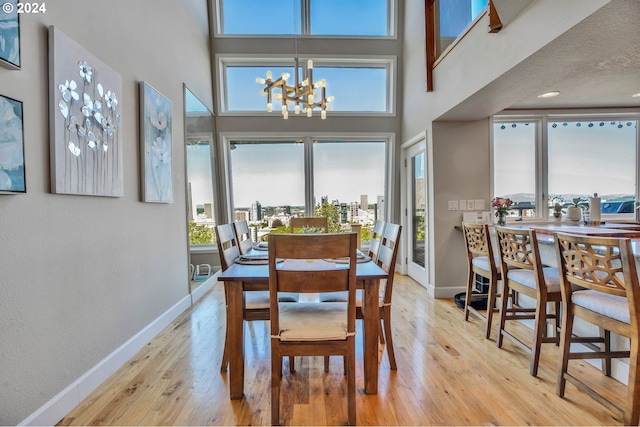 dining area with light hardwood / wood-style floors, plenty of natural light, and a high ceiling