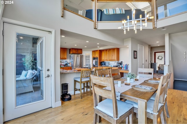 dining room featuring a notable chandelier, light wood-type flooring, and a high ceiling