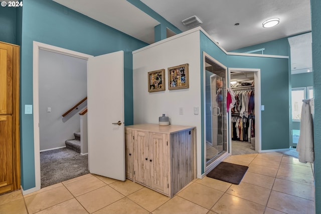 hall featuring vaulted ceiling and light tile patterned floors