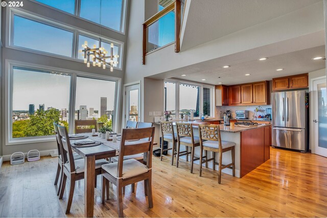 dining space featuring a chandelier, a high ceiling, light wood-type flooring, and plenty of natural light