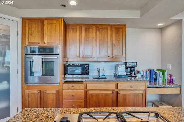 kitchen with oven, a textured ceiling, and a tray ceiling