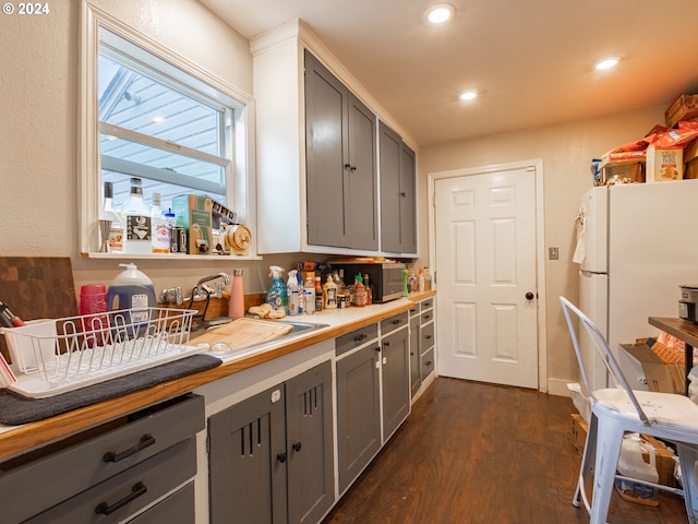 kitchen featuring gray cabinetry, dark hardwood / wood-style flooring, white fridge, and sink