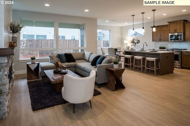 living room featuring a fireplace, sink, and light hardwood / wood-style floors