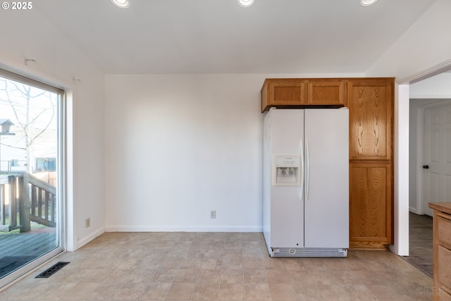 kitchen featuring lofted ceiling and white refrigerator with ice dispenser