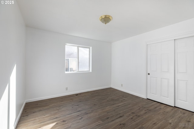 unfurnished bedroom featuring dark hardwood / wood-style flooring and a closet