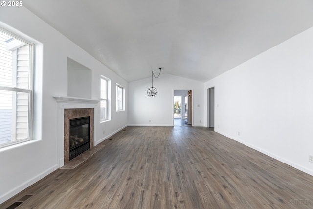 unfurnished living room with dark hardwood / wood-style flooring, a tile fireplace, and lofted ceiling