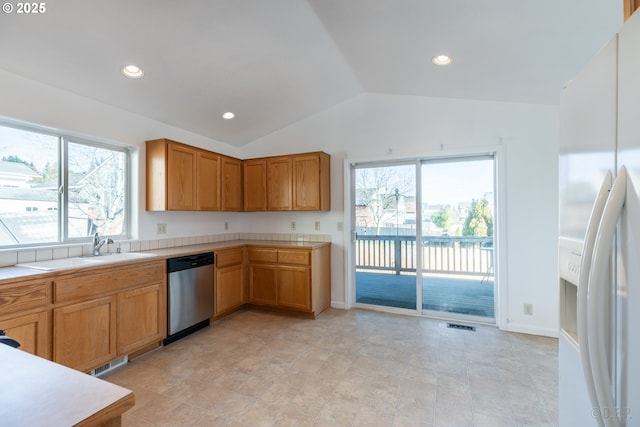 kitchen with lofted ceiling, sink, stainless steel dishwasher, and white fridge with ice dispenser