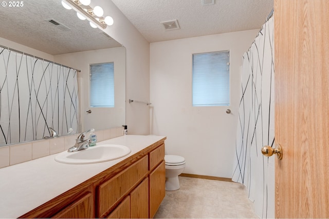 bathroom featuring vanity, toilet, and a textured ceiling