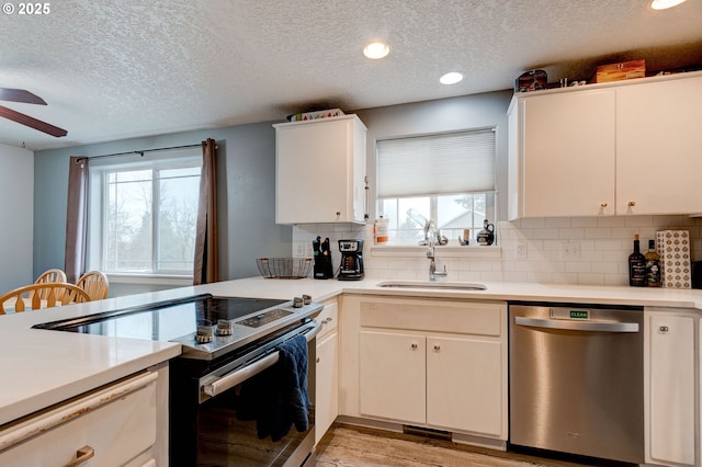 kitchen with appliances with stainless steel finishes, a textured ceiling, sink, light hardwood / wood-style flooring, and white cabinetry