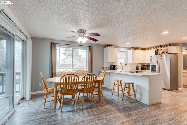 dining room with ceiling fan, light hardwood / wood-style floors, and a textured ceiling