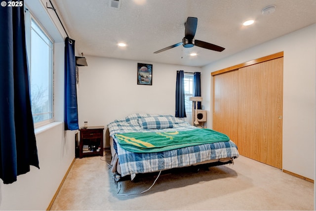 carpeted bedroom featuring a textured ceiling, a closet, and ceiling fan