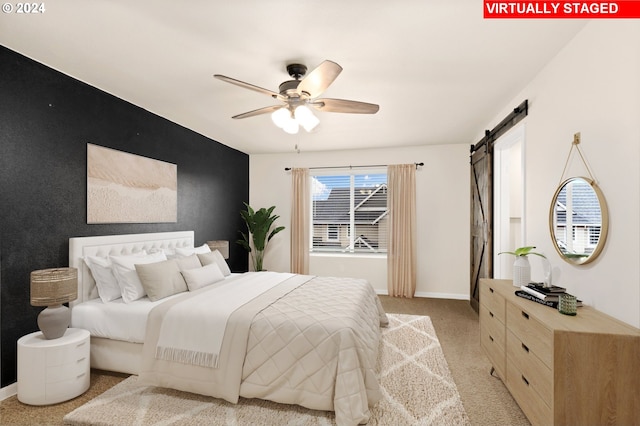 carpeted bedroom with ceiling fan and a barn door