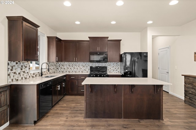 kitchen featuring sink, hardwood / wood-style floors, black appliances, and a center island