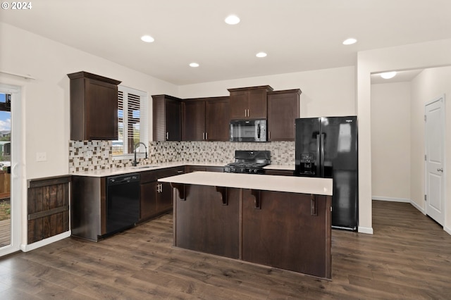 kitchen featuring a center island, black appliances, sink, a kitchen breakfast bar, and dark hardwood / wood-style flooring