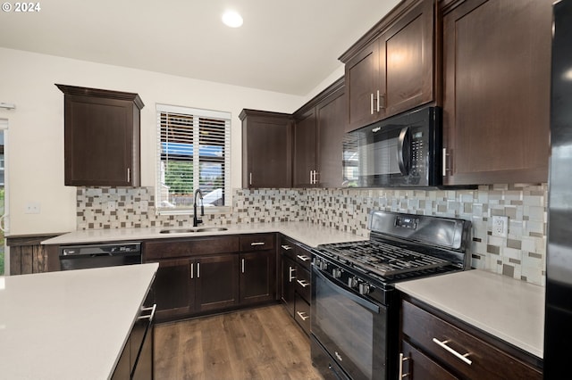 kitchen featuring sink, wood-type flooring, black appliances, and tasteful backsplash