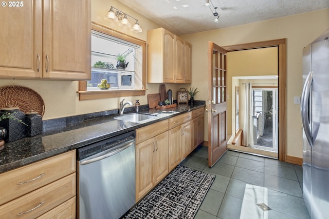 3329 SE Steele St, Portland, OR 97202 - kitchen with stainless steel appliances, light brown cabinetry, tile patterned flooring, dark stone counters, and rail lighting