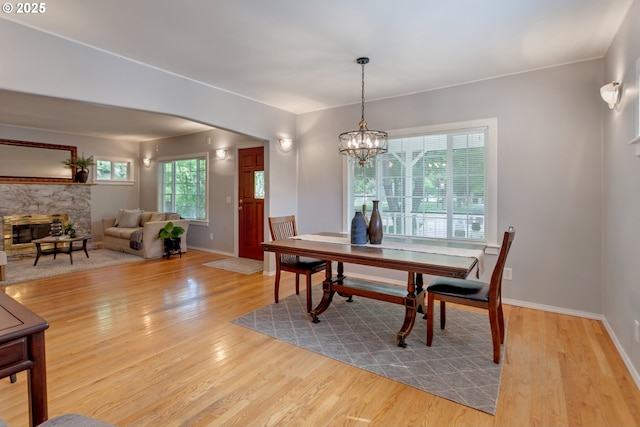 3329 SE Steele St, Portland, OR 97202 - dining room featuring wood finished floors, a stone fireplace, and a chandelier