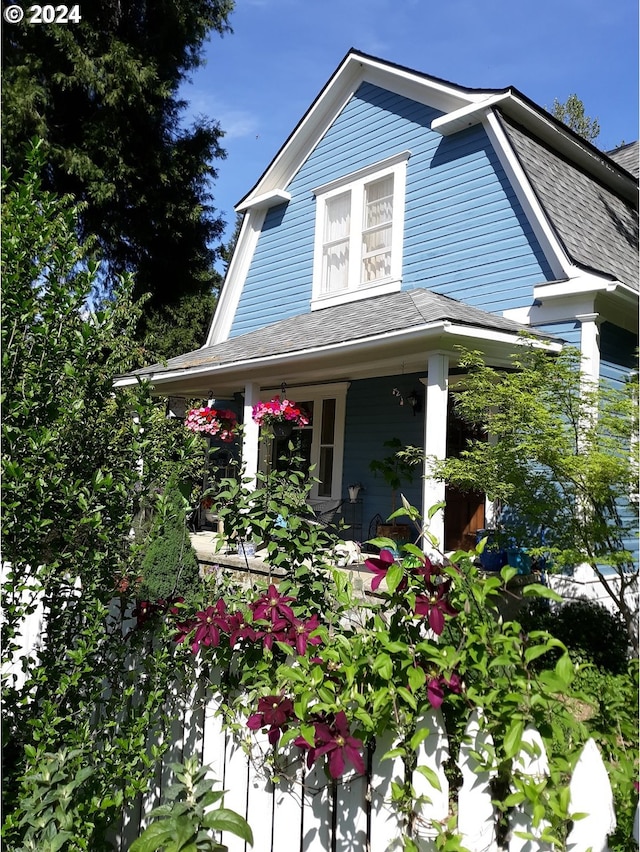 exterior space featuring a porch and roof with shingles