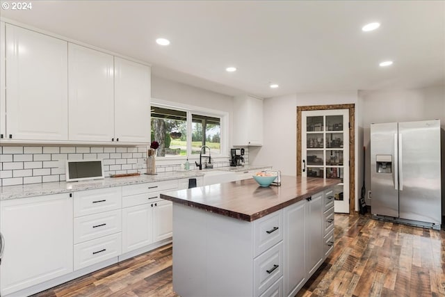 kitchen featuring a center island, dark wood-type flooring, white cabinets, stainless steel fridge with ice dispenser, and butcher block counters