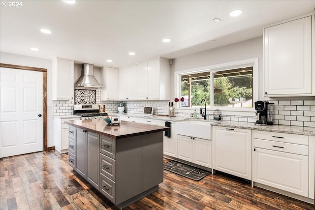 kitchen with white cabinetry, a kitchen island, and wall chimney range hood