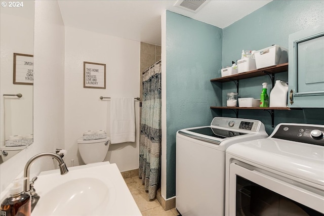 washroom featuring light tile patterned flooring, washing machine and dryer, and sink