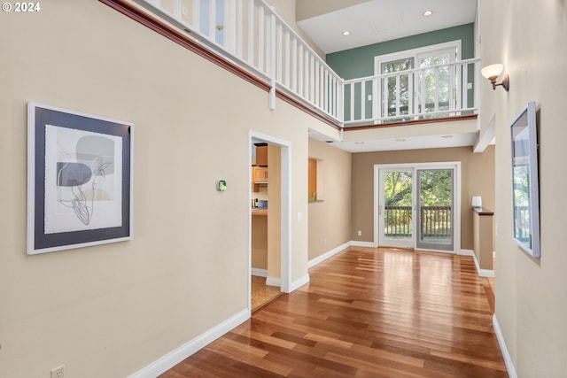 interior space featuring a towering ceiling and wood-type flooring